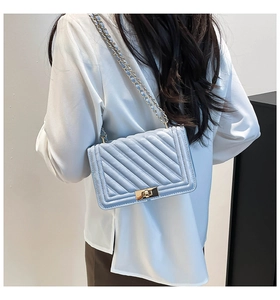 Gros plan d'un sac bandoulière matelassé bleu clair porté par un mannequin, style moderne