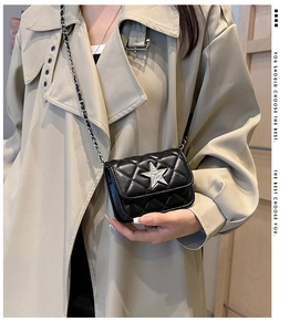 Detail of black quilted mini bag with silver star crystal and chain strap on coat