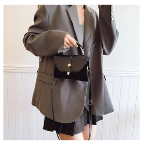 Détail du petit sac carré noir avec fermoir métallique doré et bandoulière réglable