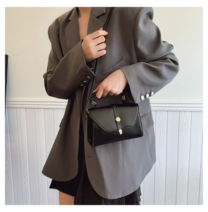 Sac à main en cuir noir avec fermoir doré porté à l'épaule pour un style chic
