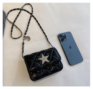 Macro shot of black quilted mini bag with silver star emblem next to a smartphone