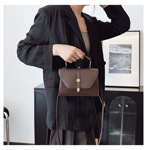 Détail du sac à main marron foncé avec boucle rotative dorée en situation de style de vie