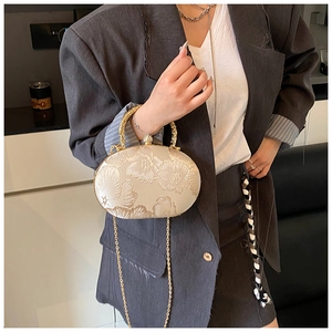 Dettaglio ricamo floreale su pochette in raso bianco crema con manico e catena