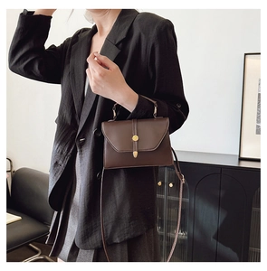 Détail d'un sac enveloppe en cuir mat marron foncé avec boucle dorée élégante