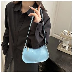 Détail du sac demi-lune en cuir verni bleu clair avec fermeture éclair dorée sur mannequin