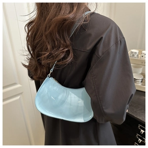 Vue arrière d'un mannequin portant un sac sous le bras en cuir verni bleu clair moderne