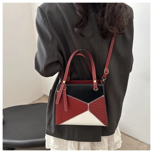 Detail of red and black leather handbag with woven texture and white contrast stitching