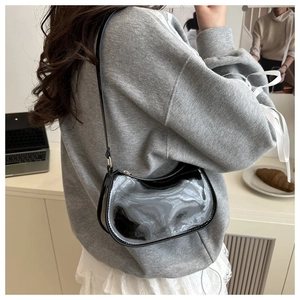 Détail d'un sac à bandoulière en cuir verni noir brillant avec une forme de demi-lune