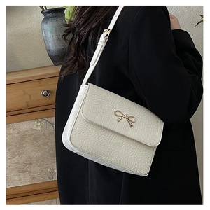 Gros plan d'un sac blanc à motif crocodile avec une boucle en métal en forme de nœud