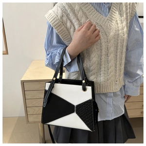 Detail view of contrast stitching and woven texture on a black and white handbag