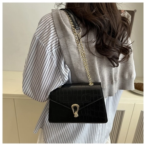 Close-up of black crocodile pattern crossbody bag with gold U-shaped metal buckle