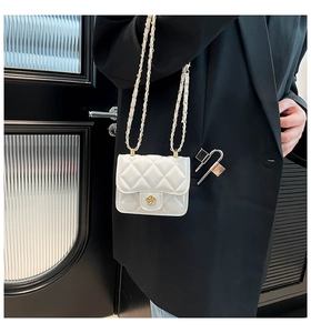 Détail du mini sac blanc matelassé avec fermoir fleur dorée et bandoulière chaîne