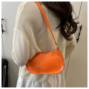 Modèle portant un sac à bandoulière en cuir verni orange vif en forme de croissant