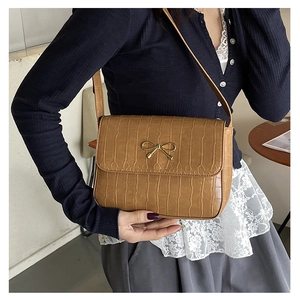 Close-up of brown crocodile texture bag featuring a vintage golden bow buckle detail