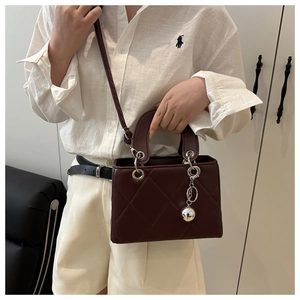 Detail of burgundy quilted leather square handbag with silver metal ball pendant and ring handle
