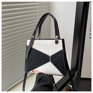 Detail of geometric patchwork leather handbag with woven texture and contrast stitching