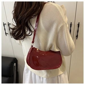 Sac croissant en cuir verni bordeaux porté par un mannequin pour le style