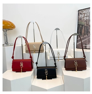 Five minimalist leather underarm bags in various colors with gold S-logo and tassel detail