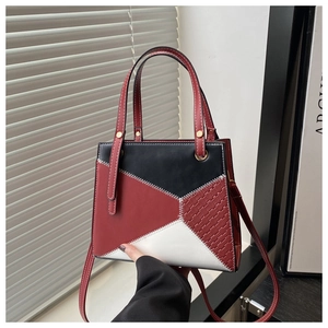 Close-up of geometric mini handbag with red black white stitching and woven texture details