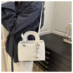 Detail of white quilted mini square bag with silver ball charm and adjustable strap