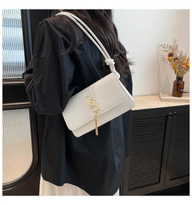 Detailed shot of white faux crocodile leather bag with gold buckle and long fringe tassel