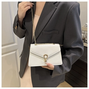 Detailed view of white crocodile pattern crossbody bag with golden chain on a model