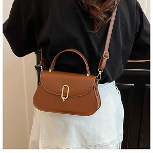 Detailed back view of a woman wearing a vintage brown crossbody bag with gold buckle