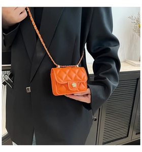 Close-up of a mini orange quilted chain bag with a decorative floral clasp for lipsticks
