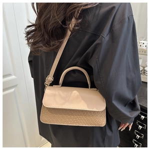 Detail of beige shoulder bag with unique woven texture and smooth leather flap