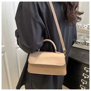 Detail of beige crossbody bag featuring crocodile pattern texture and adjustable strap
