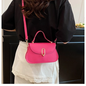 Detail of fuchsia crossbody bag featuring a gold oval lock and elegant top handle
