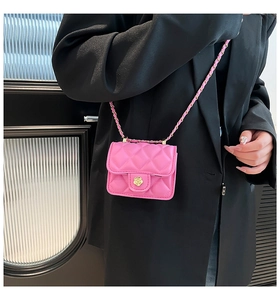 Detail of rose pink quilted crossbody bag with a golden camellia flower clasp on a model