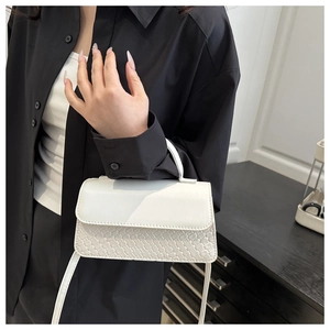 Detail showing the white woven leather texture and crossbody strap of this square bag
