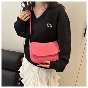 Detail of bright pink PU leather shoulder bag worn by model with adjustable strap