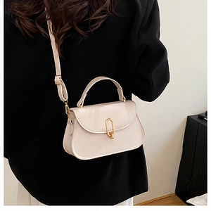 Chic cream leather handbag featuring a glossy finish and a gold oval metal clasp detail