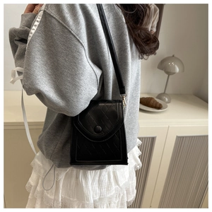 Close-up of a black quilted leather phone bag with elegant shoulder strap detail