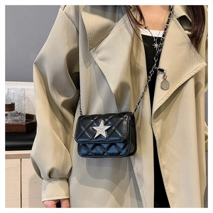 Detail of black quilted mini crossbody bag with silver star and chain strap