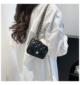 Gros plan du mini sac matelassé noir avec fermoir fleur dorée et bandoulière chaîne