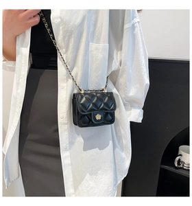 Close-up of black quilted micro crossbody bag with camellia flower clasp and chain strap