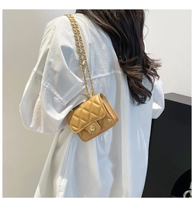 Detail of yellow quilted mini bag with golden camellia clasp and chain strap