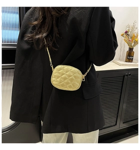 Close-up of yellow quilted mini chain bag worn with a black blazer and blue pants