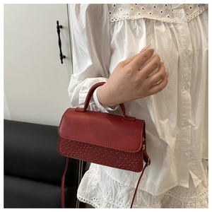 Detail of red PU leather handbag with woven texture and adjustable shoulder strap