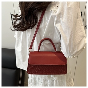Side view of red textured woven leather handbag with gold hardware on a model