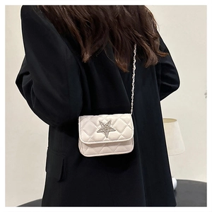 Close-up of a white quilted crossbody bag featuring a sparkling star and chain strap