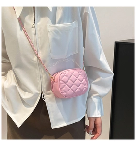 Detail of pink quilted crossbody camera bag with gold metal and leather chain strap