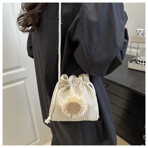 Detail of hand-woven straw bucket bag with sunflower decor and drawstring closure