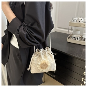 Detail of a mini straw bucket bag featuring a sunflower accent and drawstring closure