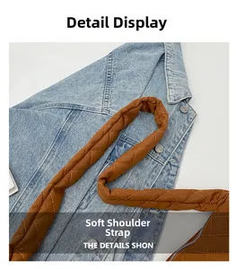 Détail de la bandoulière matelassée marron avec boucle en métal sur veste en jean