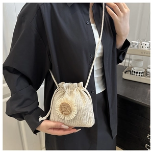 Detail of a beige woven bucket bag featuring a sunflower ornament and a drawstring closure