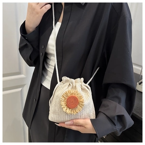 Detail of a beige woven bucket bag featuring a vibrant 3D sunflower and drawstring closure